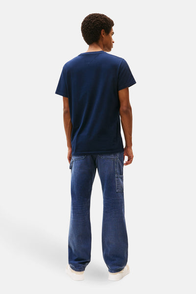Blauw T-shirt met korte mouwen van TOMMY JEANS, gedragen met een wijde jeans en witte schoenen, achtergezicht.