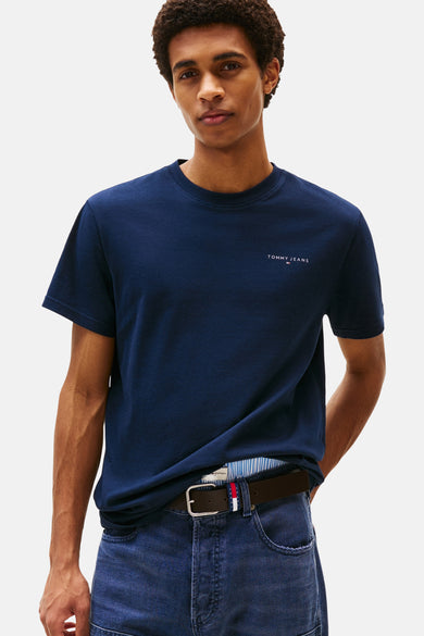 Blauw T-shirt met korte mouwen van Tommy Jeans, gedragen met een spijkerbroek en een bruine leren riem.