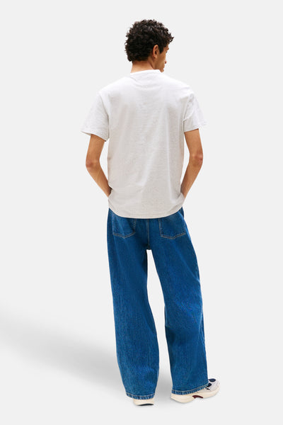 Grijze T-shirt met korte mouwen van TOMMY JEANS, gedragen met een wijde blauwe jeans.