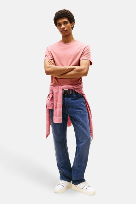 Roze T-shirt met korte mouwen van Tommy Jeans, gedragen met een overhemd dat aan de taille is geknoopt en een blauwe jeans.