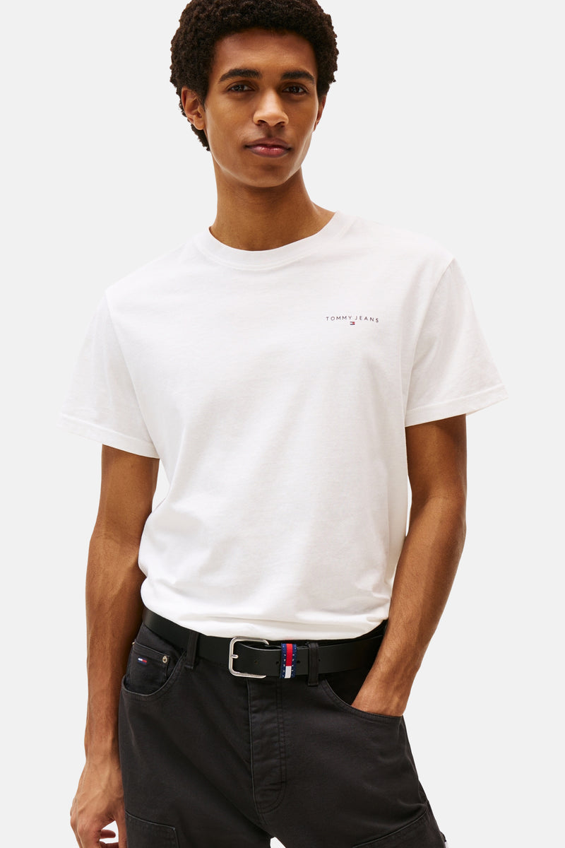 Wit T-shirt met korte mouwen van Tommy Jeans, gedragen met een wijde zwarte broek en witte sneakers.