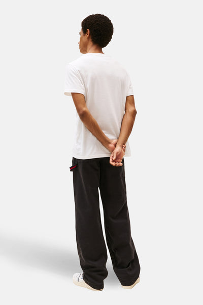 Wit T-shirt met korte mouwen van Tommy Jeans, gedragen met een wijde zwarte broek en witte sneakers.