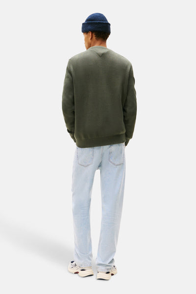 Groene trui met ronde hals van TOMMY JEANS, gedragen met een lichtblauwe jeans en een marineblauwe muts.