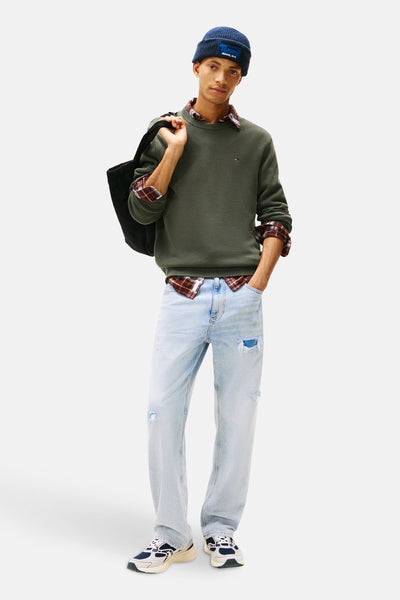 Groene rondehals trui van TOMMY JEANS gedragen over een geruit overhemd, met een verbleekte spijkerbroek en een blauwe muts.