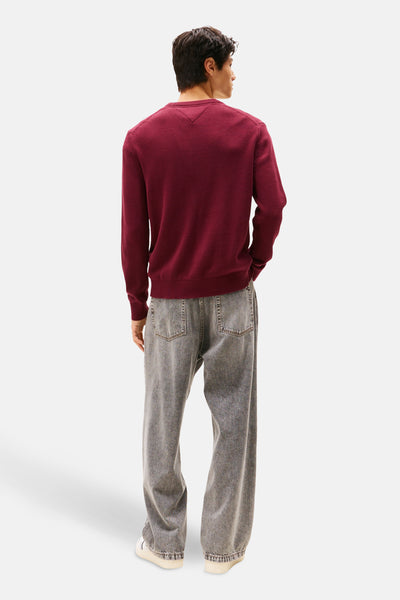 Bordeaux ronde hals trui van TOMMY JEANS, van achteren getoond, gedragen met een lichtgrijze jeans.