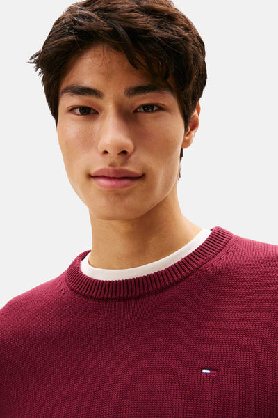 Pull bordeaux à col rond de TOMMY JEANS, porté sur un t-shirt blanc, avec logo discret.
