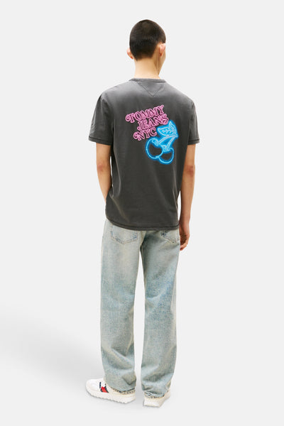 Grijze T-shirt met korte mouwen van TOMMY JEANS, met kersenprint en belettering op de rug, gedragen met een blauwe jeans.