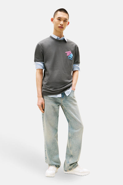 Grijze T-shirt met korte mouwen van TOMMY JEANS, gedragen met een gestreept overhemd en een verbleekte spijkerbroek.