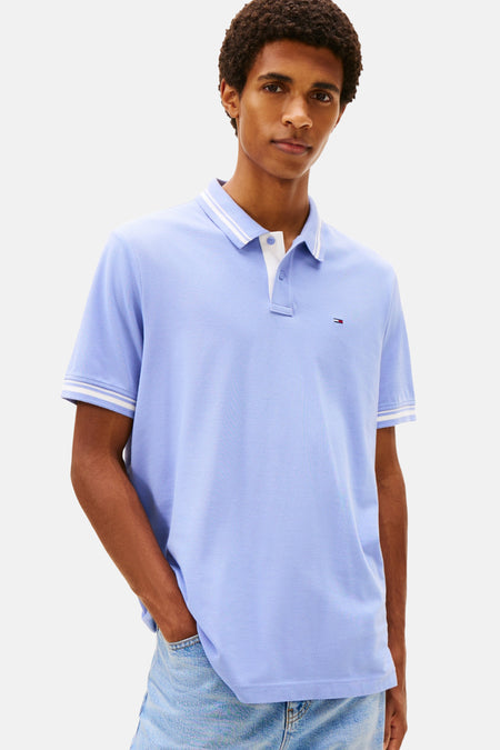 Paarse polo met korte mouwen van TOMMY JEANS, gedragen met een crèmekleurige trui geknoopt over de schouders.