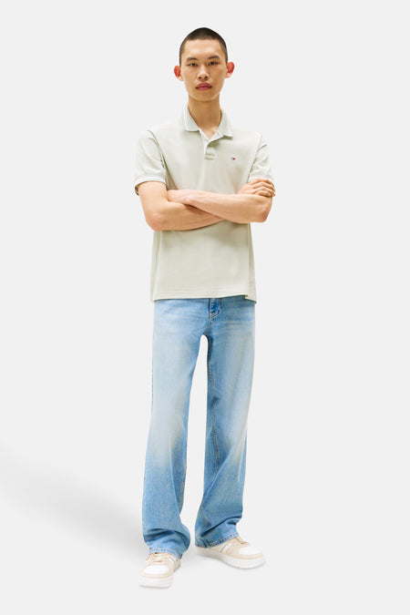 Mintgroen poloshirt met korte mouwen van TOMMY JEANS, gedragen met een wijde, uitgewassen spijkerbroek en neutrale sneakers.