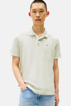 Polo vert clair à manches courtes de Tommy Jeans, avec col et bordures rayés, porté avec un jean bleu.

