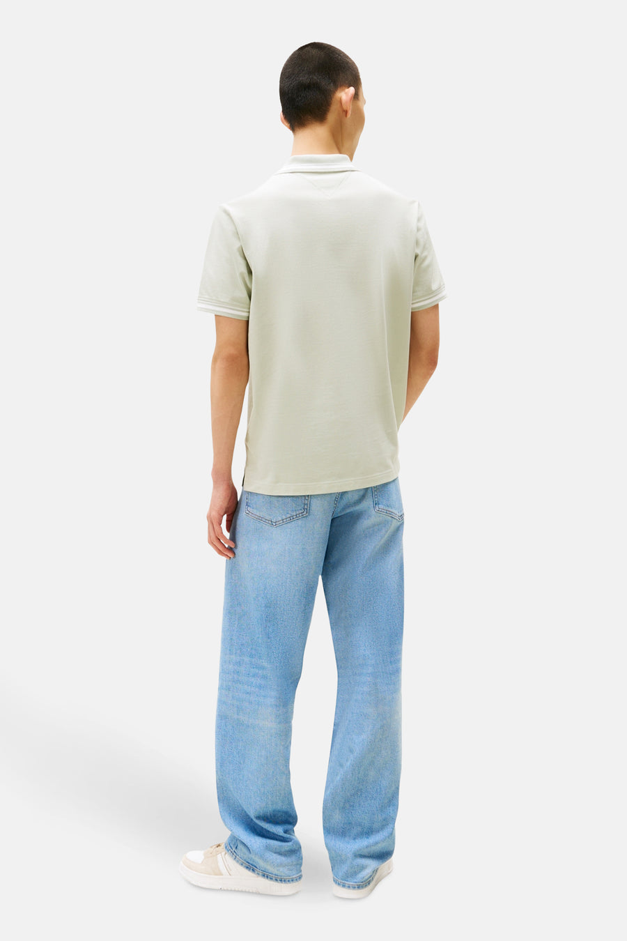 Polo à manches courtes vert de TOMMY JEANS avec bordure blanche au bout des manches, porté avec un jean ample.