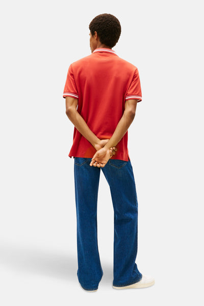 Polo rouge à manches courtes de TOMMY JEANS, avec des rayures blanches au col et aux manches.
