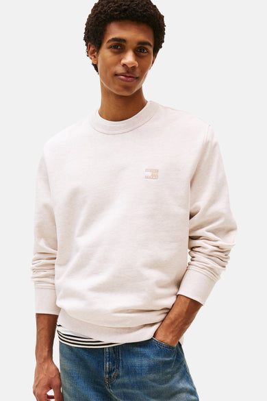 Sweat-shirt beige de TOMMY JEANS, avec un logo discret et porté avec un jean.