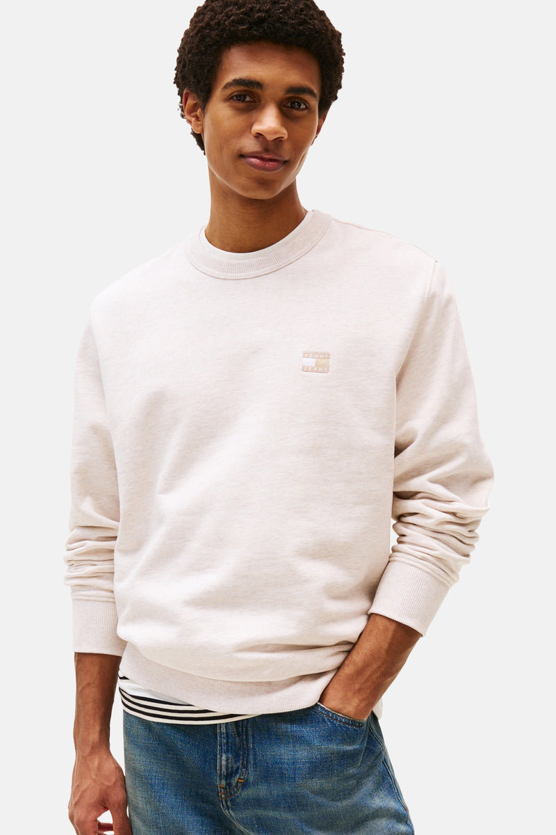 Sweat-shirt beige de TOMMY JEANS, avec un logo discret et porté avec un jean.