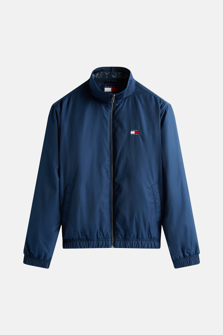 Imperméable bleu par TOMMY JEANS avec fermeture à glissière, col montant et logo sur la poitrine.