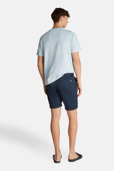 Short bleu de TOMMY JEANS, porté avec un t-shirt bleu clair et des tongs noires.