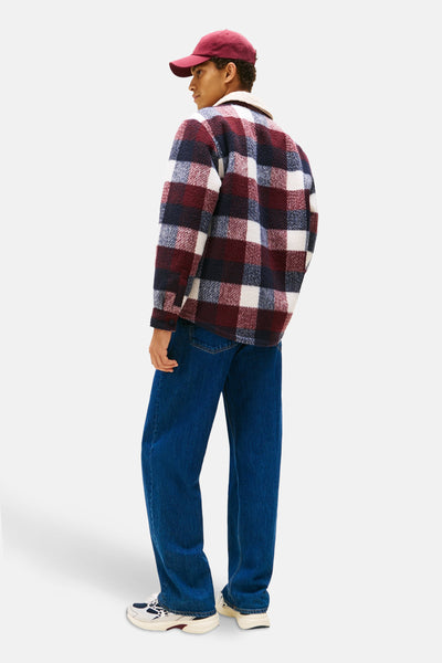 Multikleuren geruit overhemd van TOMMY JEANS, gedragen met een rode hoed en een wijde blauwe spijkerbroek.