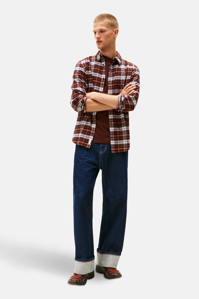 Bruin geruit flanellen overhemd met lange mouwen van TOMMY JEANS, gedragen over een bruin T-shirt en een wijde jeans.