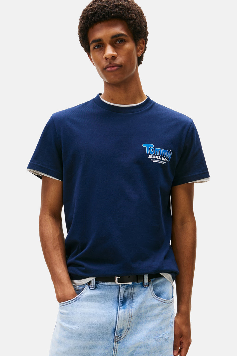 Blauw T-shirt met korte mouwen van TOMMY JEANS, met logo opdruk op de voorkant, gedragen met een lichte spijkerbroek.