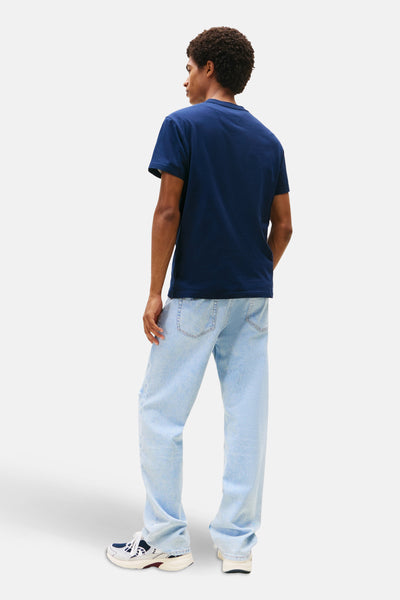 Blauw T-shirt met korte mouwen van TOMMY JEANS, gedragen met een verbleekte spijkerbroek en sneakers.