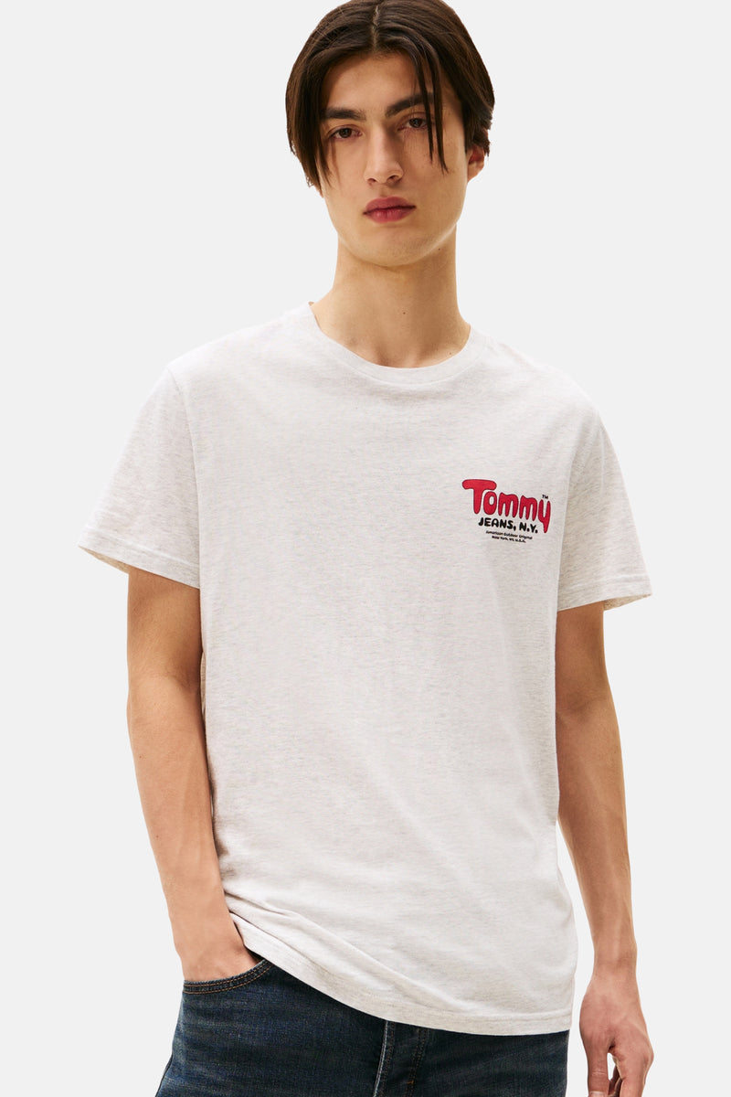 Grijze gemêleerde T-shirt met korte mouwen van Tommy Jeans, met rood logo op de voorkant en gedragen met een donkerblauwe jeans.