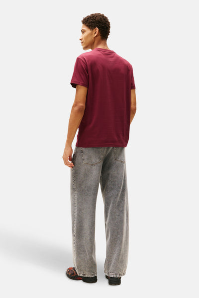 Rood T-shirt met korte mouwen van TOMMY JEANS, gedragen met een lichtgrijze jeans en sneakers. Achterzicht.