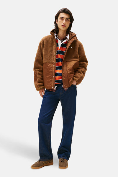 Veste brune en sherpa par Tommy Jeans, portée avec un polo rayé et un jean bleu foncé.