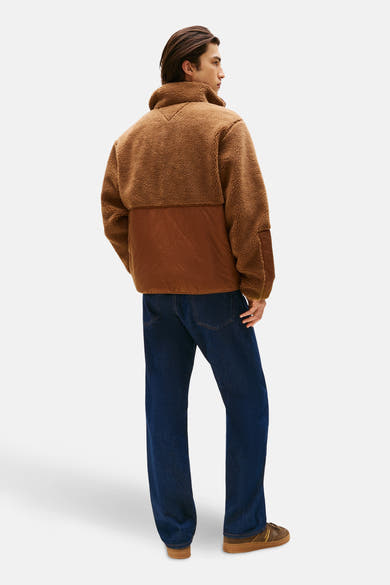 Bruin fleecejack van TOMMY JEANS, met gewatteerd inzetstuk en gedragen met een blauwe spijkerbroek en bruine schoenen.