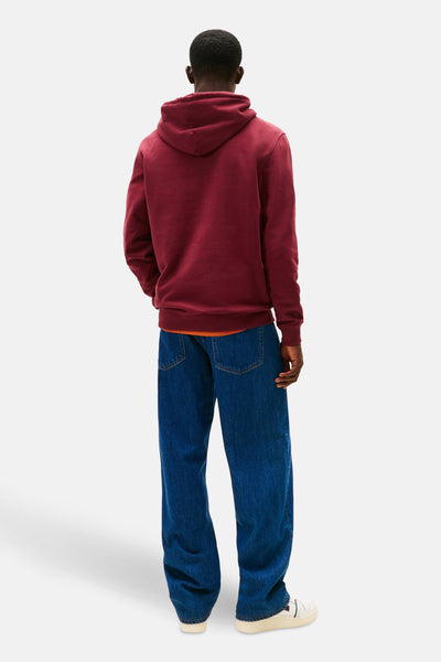 Rode TOMMY JEANS hoodie, met oranje voering, gedragen met een wijde blauwe jeans en witte sneakers.