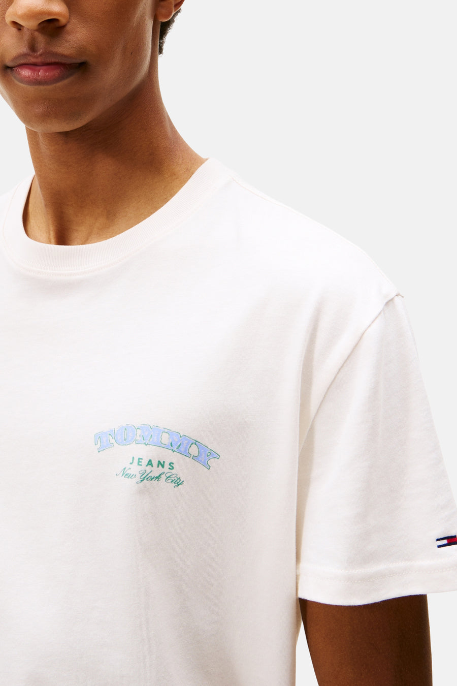 Ecru T-shirt met korte mouwen van Tommy Jeans met een geflockt logo op de voorkant en een vlagdetail op de mouw.