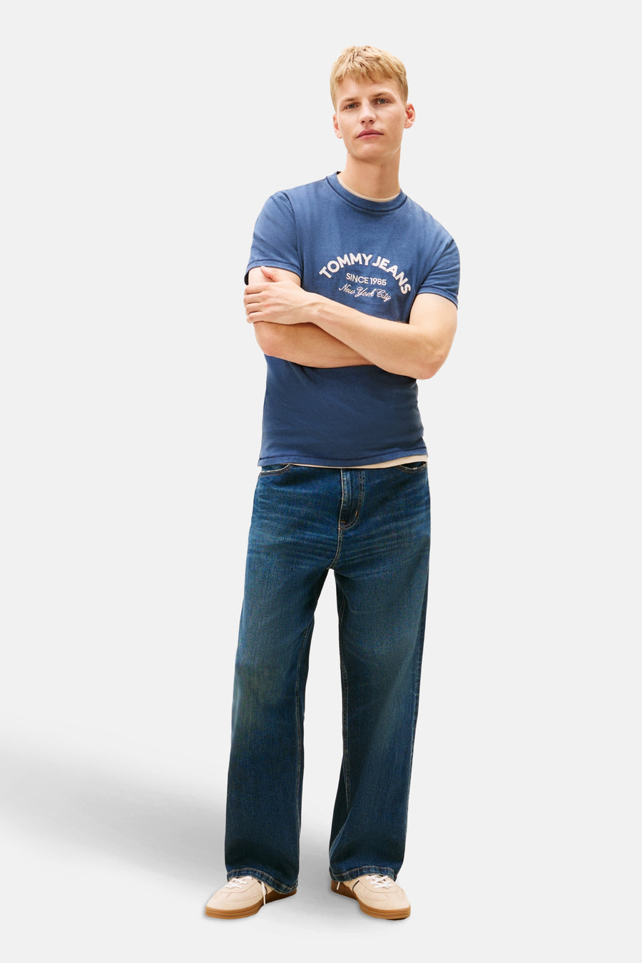 Blauw T-shirt met korte mouwen van TOMMY JEANS, gedragen met een wijde blauwe jeans en beige sneakers.