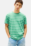 T-shirt à manches courtes vert rayé de TOMMY JEANS, porté avec un jean en denim clair.
