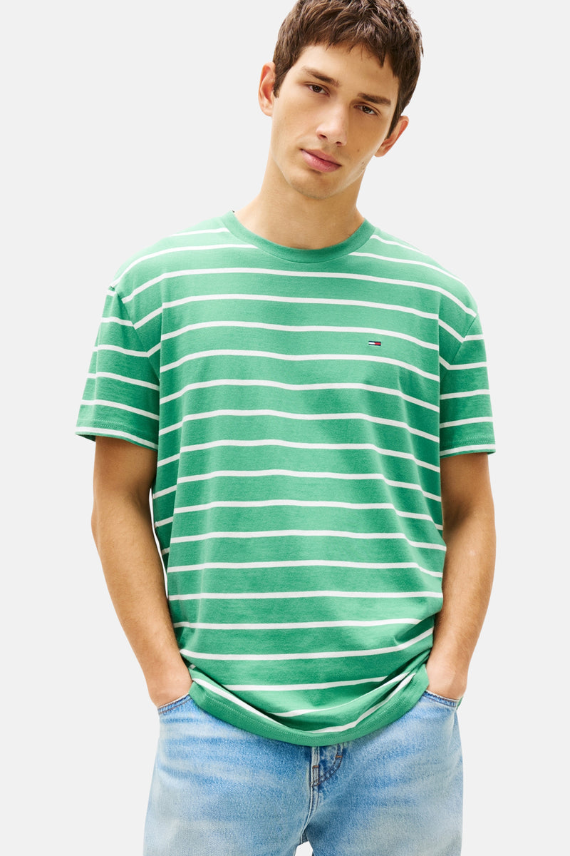 T-shirt à manches courtes vert rayé de TOMMY JEANS, porté avec un jean en denim clair.
