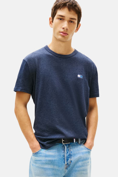 Blauw T-shirt met korte mouwen van TOMMY JEANS, gedragen met een casual spijkerbroek en een zwarte riem.