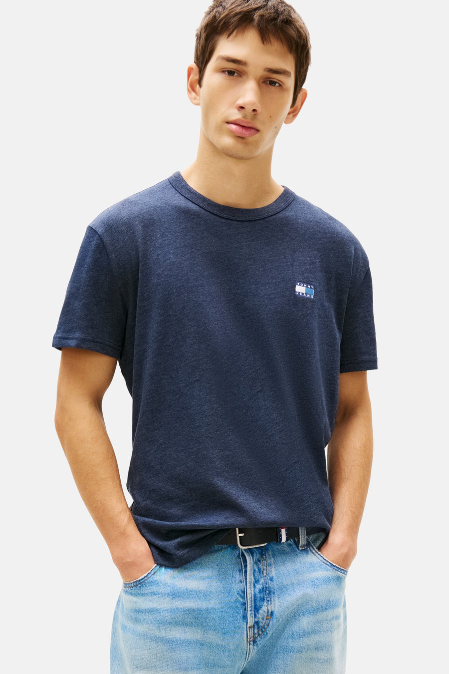 Blauw T-shirt met korte mouwen van TOMMY JEANS, gedragen met een casual spijkerbroek en een zwarte riem.