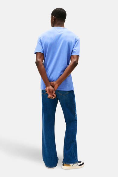 T-shirt bleu à manches courtes de TOMMY JEANS, porté avec un jean et des chaussures de sport, vue de dos.