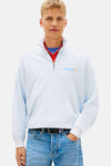 Blauwe sweater met opstaande kraag van TOMMY JEANS, gedragen met een blauwe jeans en marineblauwe en witte sneakers.
