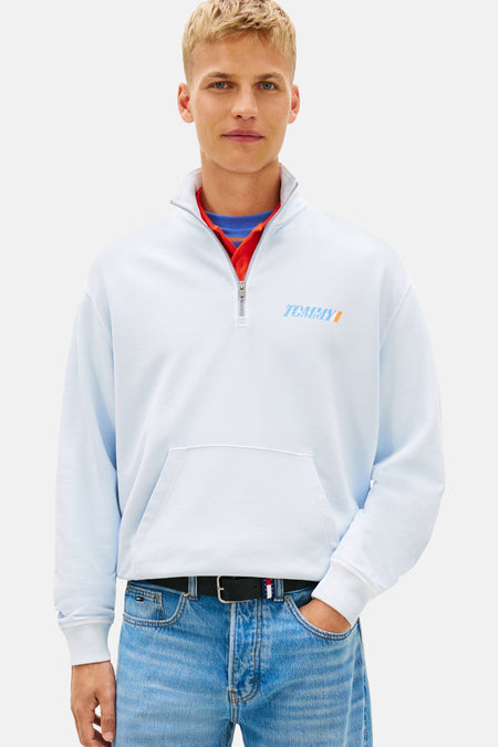 Blauwe sweater met opstaande kraag van TOMMY JEANS, gedragen met een blauwe jeans en marineblauwe en witte sneakers.