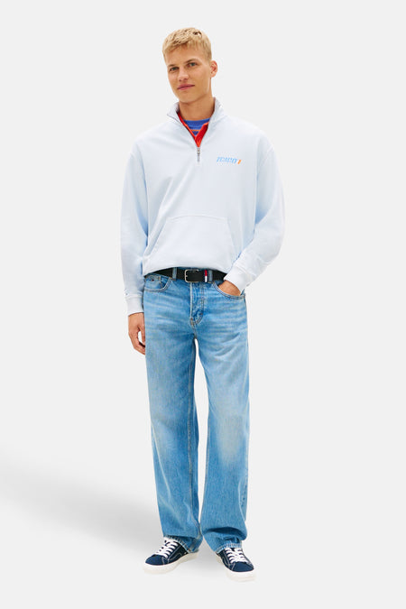 Sweat col montant bleu de TOMMY JEANS, porté avec un jean bleu et des baskets marine et blanches.