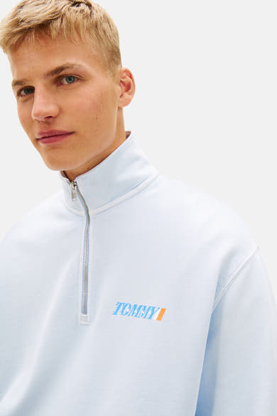 Blauwe sweater met opstaande kraag van TOMMY JEANS met ritssluiting en een opdruk van het logo op de voorkant.