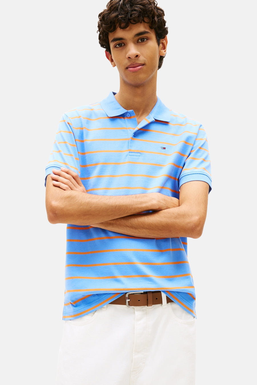 Blauwe gestreepte polo, van TOMMY JEANS, gedragen met een witte broek en bruine schoenen.