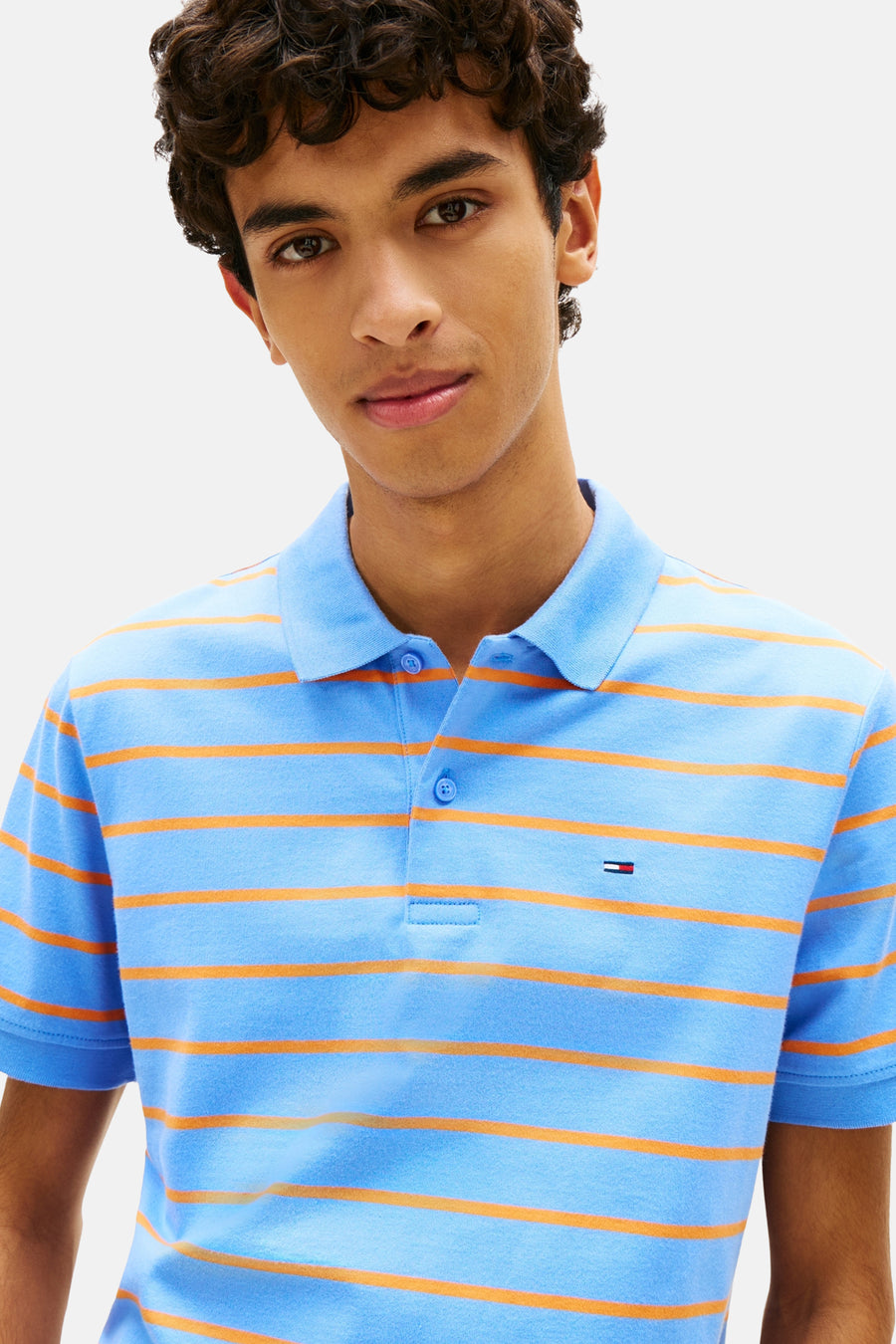 Blauwe gestreepte polo van TOMMY JEANS met oranje strepen, korte mouwen en een discreet logo op de borst.