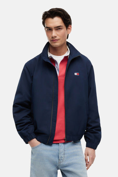 Blauwe regenjas van Tommy Jeans, met zilveren ritssluiting en logo op de borst.
