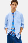 Lichtblauwe blouse met lange mouwen van TOMMY JEANS, open gedragen over een gestreept T-shirt, met een wijde jeans.