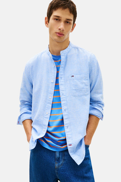 Chemise manches longues bleu, de TOMMY JEANS, avec poche poitrine et t-shirt rayé orange visible.

