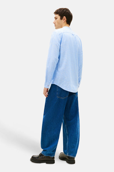 Chemise bleue à manches longues de TOMMY JEANS, portée avec un jean ample et des chaussures bateau noires.
