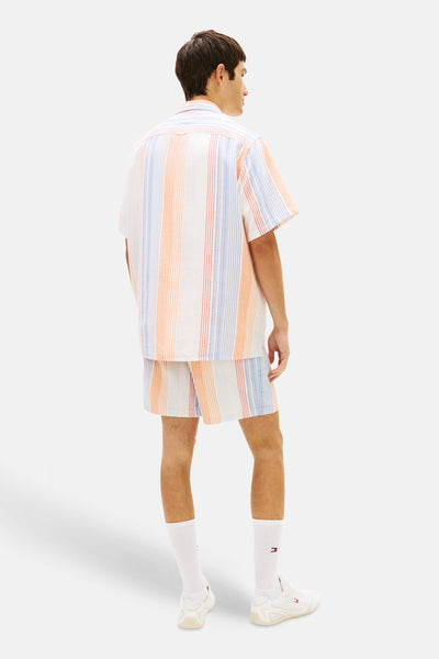 Chemise à manches courtes multicolore de TOMMY JEANS, à rayures verticales, portée avec un short assorti et des chaussettes blanches.