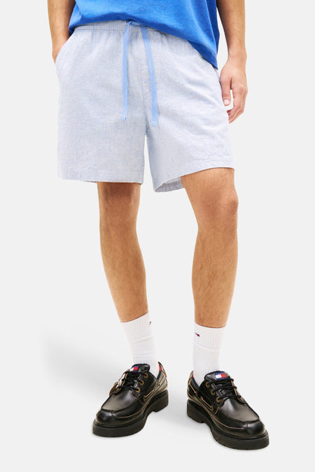 Short bleu à rayures, de TOMMY JEANS, porté avec un t-shirt bleu et des chaussures noires à plateforme.

