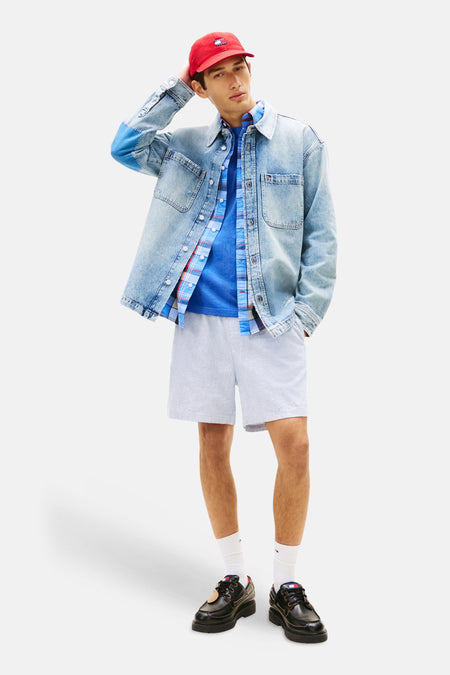 Short bleu de TOMMY JEANS, porté avec une chemise à carreaux, un t-shirt bleu et des chaussures bateau noires.